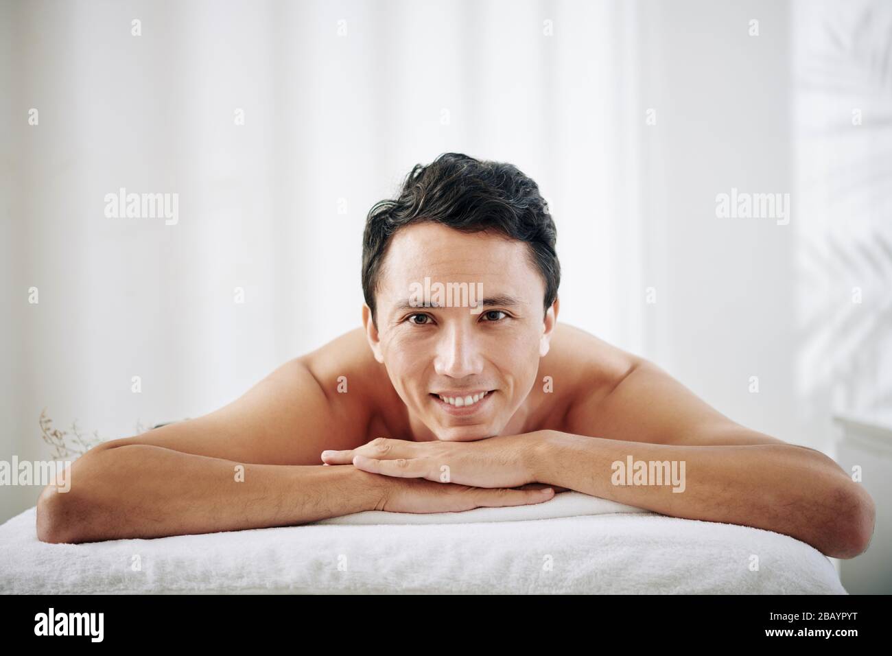 Mixed-race happy young man enjoying spending time in spa salon Stock Photo