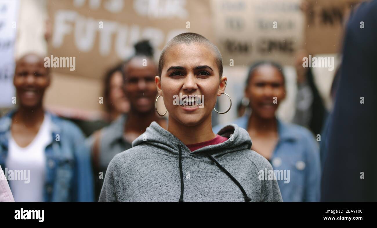 Young woman protesting with a group of people on the city street. Activists marching and protesting in the city. Stock Photo