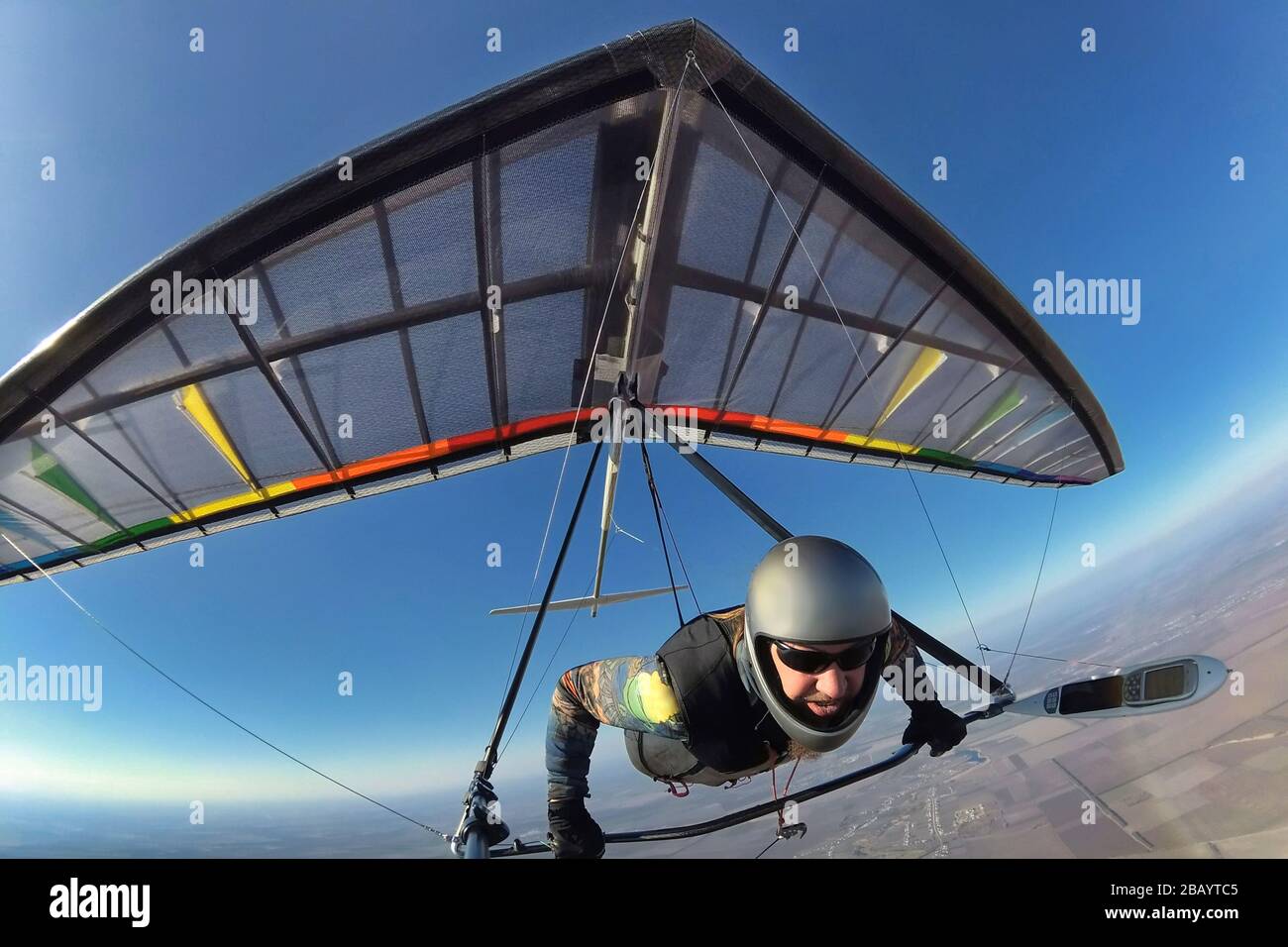 Hang glider pilot with his colorful wing flies high far away from other people. Concept of unning from crowd,self isolation and social distancing Stock Photo