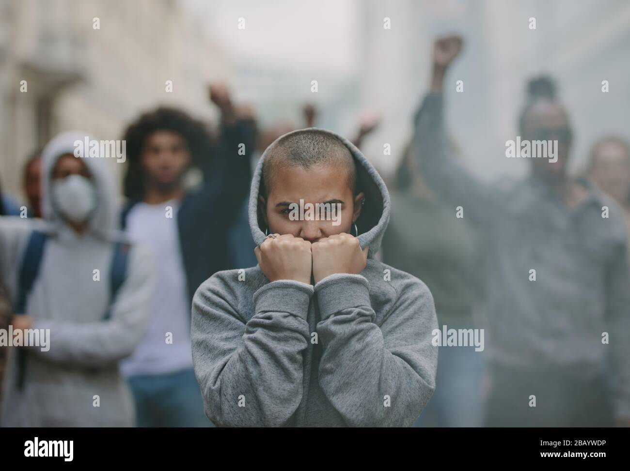 Woman in hooded shirt covering her face with her hands doing a silent protest. Group of social activists protesting silently Stock Photo