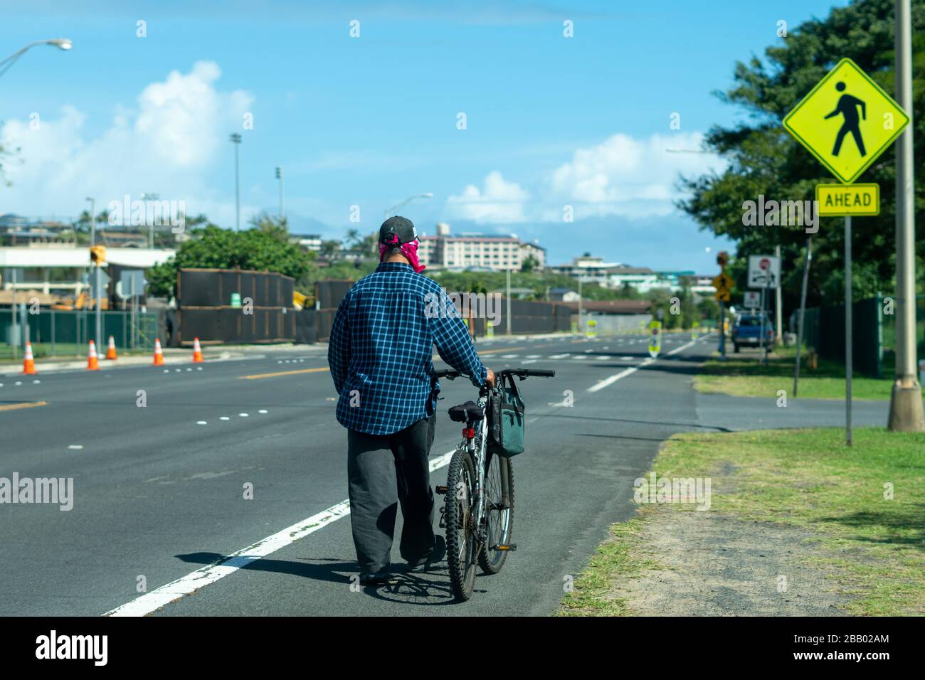 Man With a Homemade Face Mask Walks his Bike in Maui, Hawaii during Covid-19 Pandemic Stock Photo