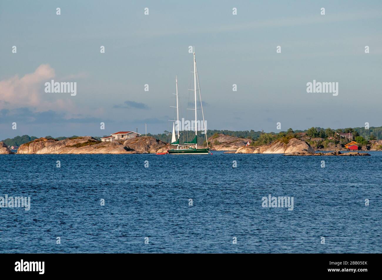 A beautiful two-masted sailboat anchored in the waters among islands and skerries in Kragerø archipelago, south Norway. Stock Photo