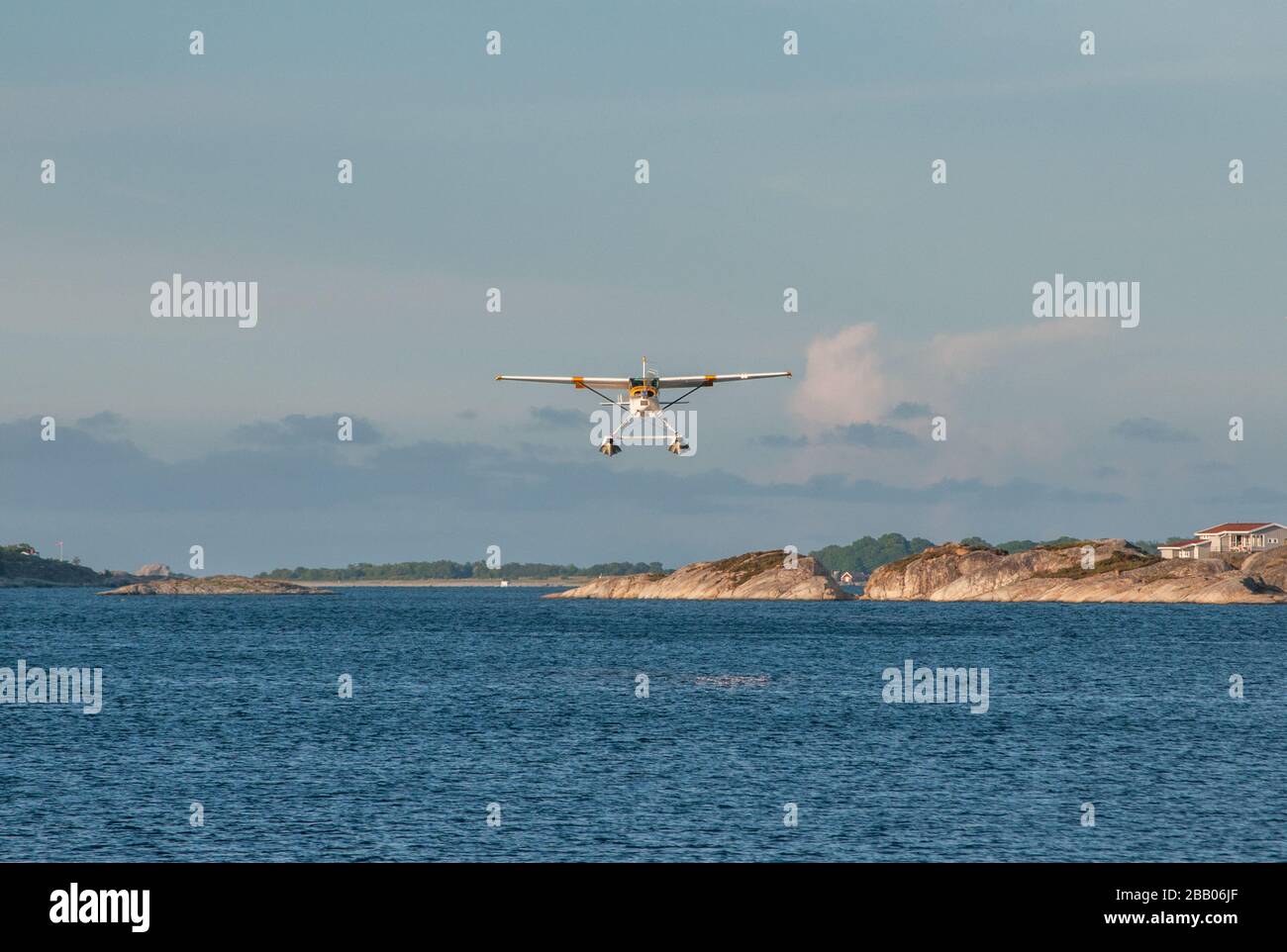 A yellow and white Cessna 172 Skyhawk seaplane taking off among islands in the Kragerø archipelago on south coast of Norway. Stock Photo