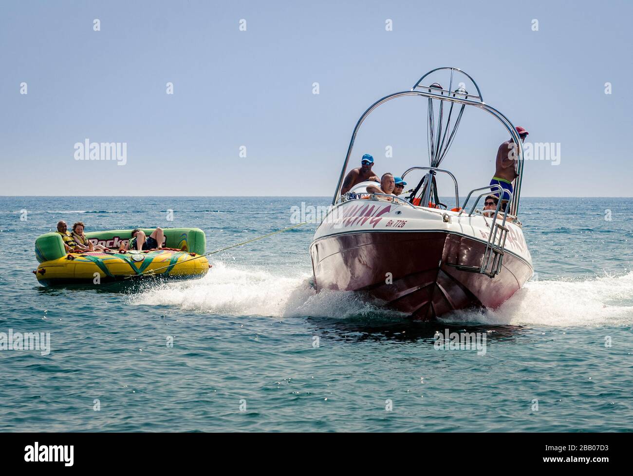 Exciting Water tubing with Power boat on the black sea towing holiday thrill seekers on a large inflatable rubber ring, long shot, Varna Bulgaria Stock Photo