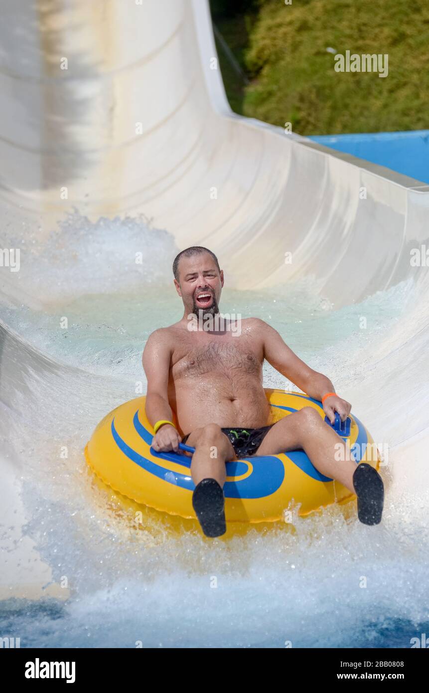 Caucasian man happily sliding down water chute on holiday at water park Varna Bulgaria Stock Photo