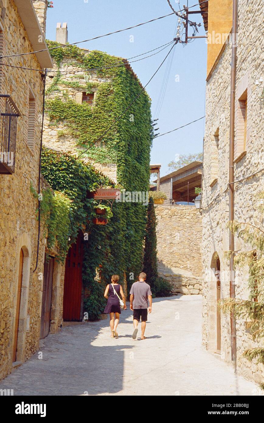 Young couple walking along the street. Peratallada, Gerona province, Catalonia, Spain. Stock Photo