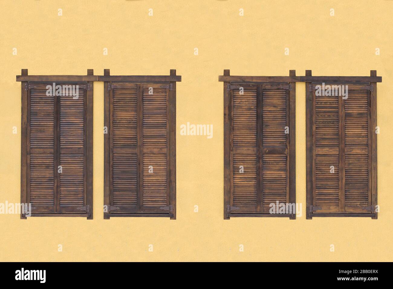 Rustic brown wooden window shutters with stone wall yellow background ...