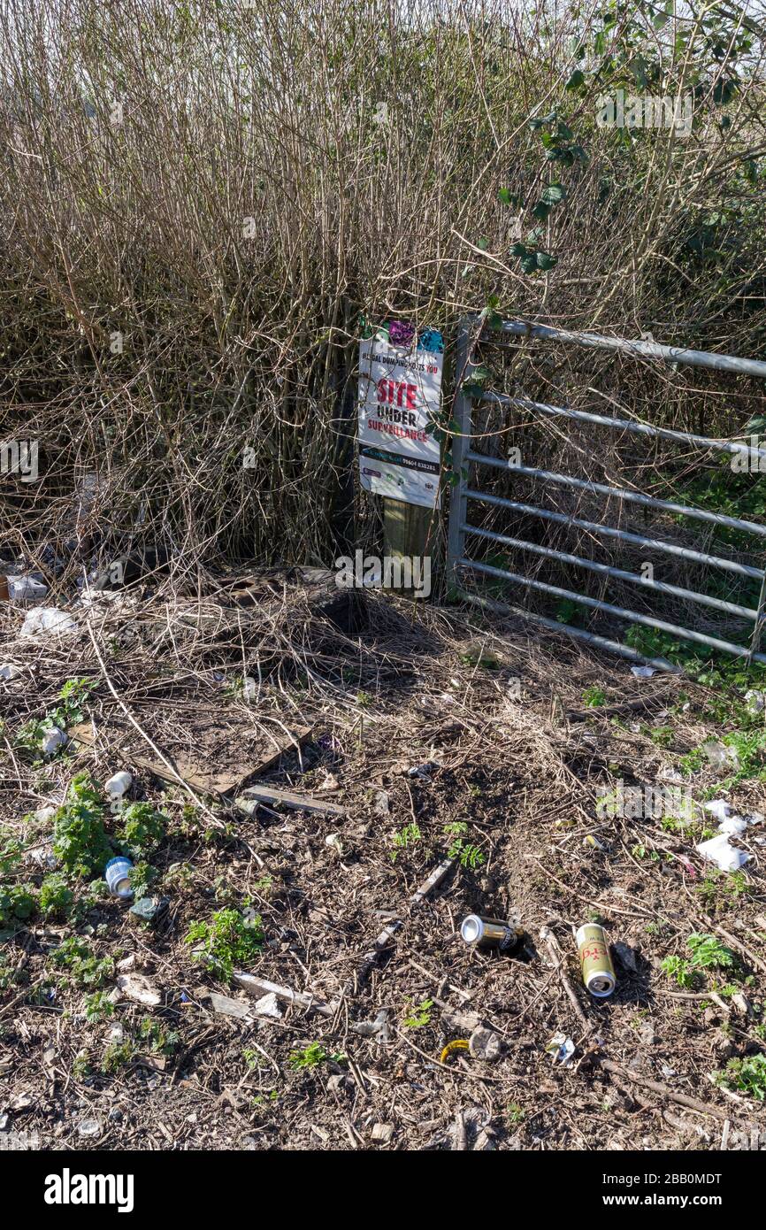 Fly tipping in an English country lane, in front of a Site Under Surveillance notice, Northampton, UK Stock Photo