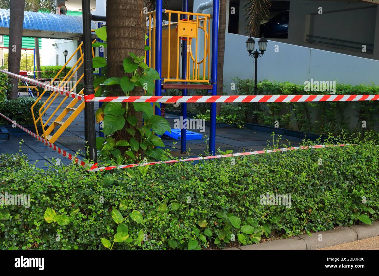 Closeup and focus on barricade tape surrounding the playground, children cannot play together, they have to keep social distancing due to coronavirus Stock Photo