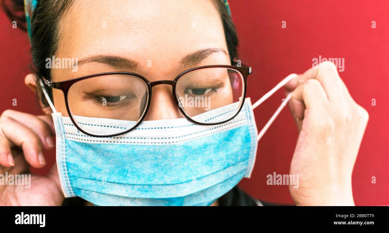 coronavirus theme. Asian woman with glasses wearing a mask to protect herself from getting infected Stock Photo