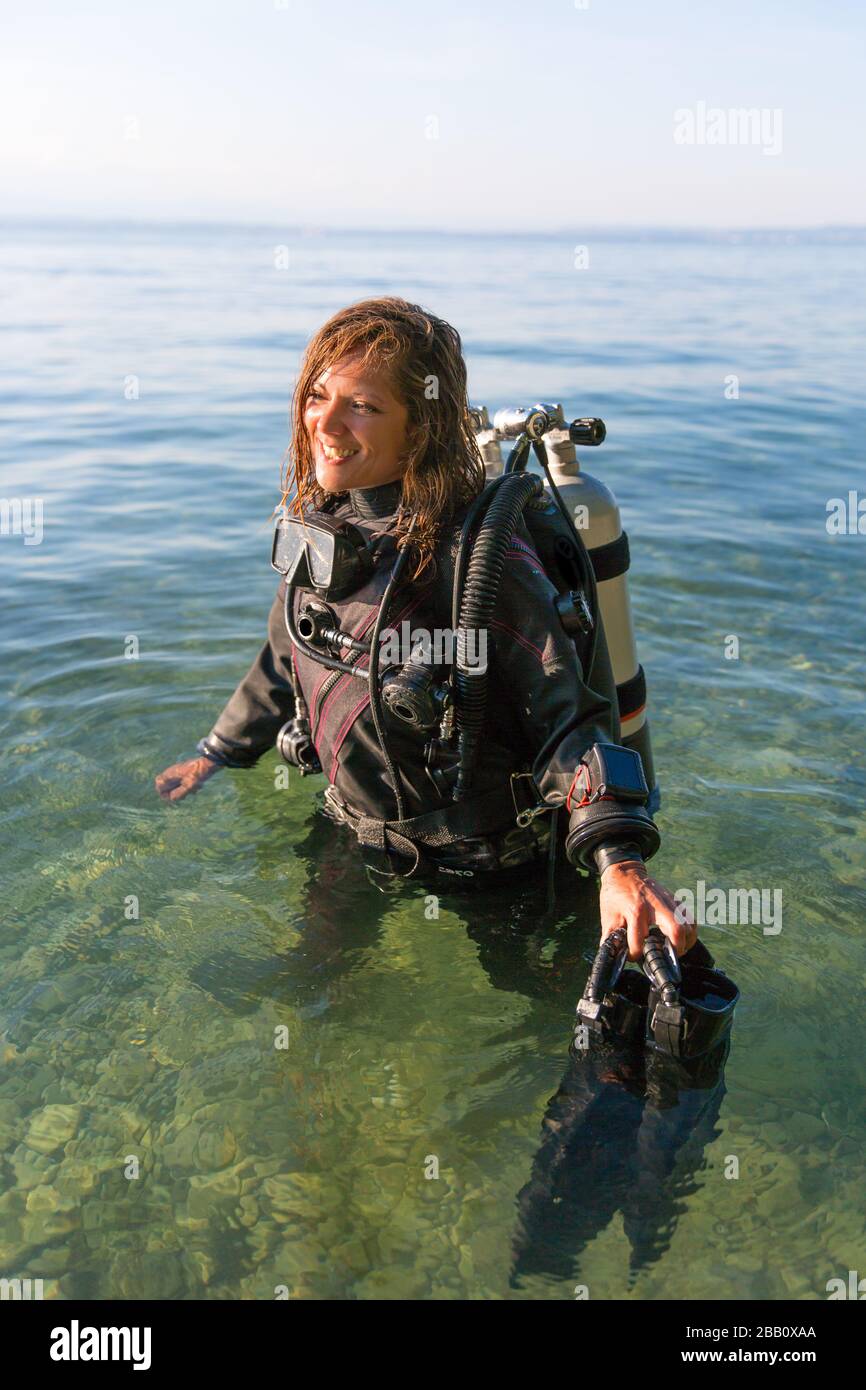 Female Scuba Diving Instructor Standing In Water Wearing A Dry Suit A