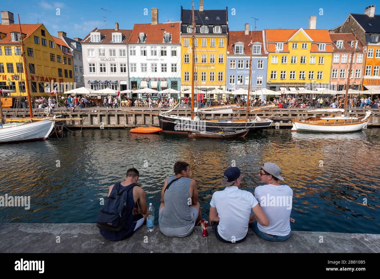 Friends hanging out on the waterfront of the Nyhavn canal in Copenhagen, Denmark, Europe Stock Photo