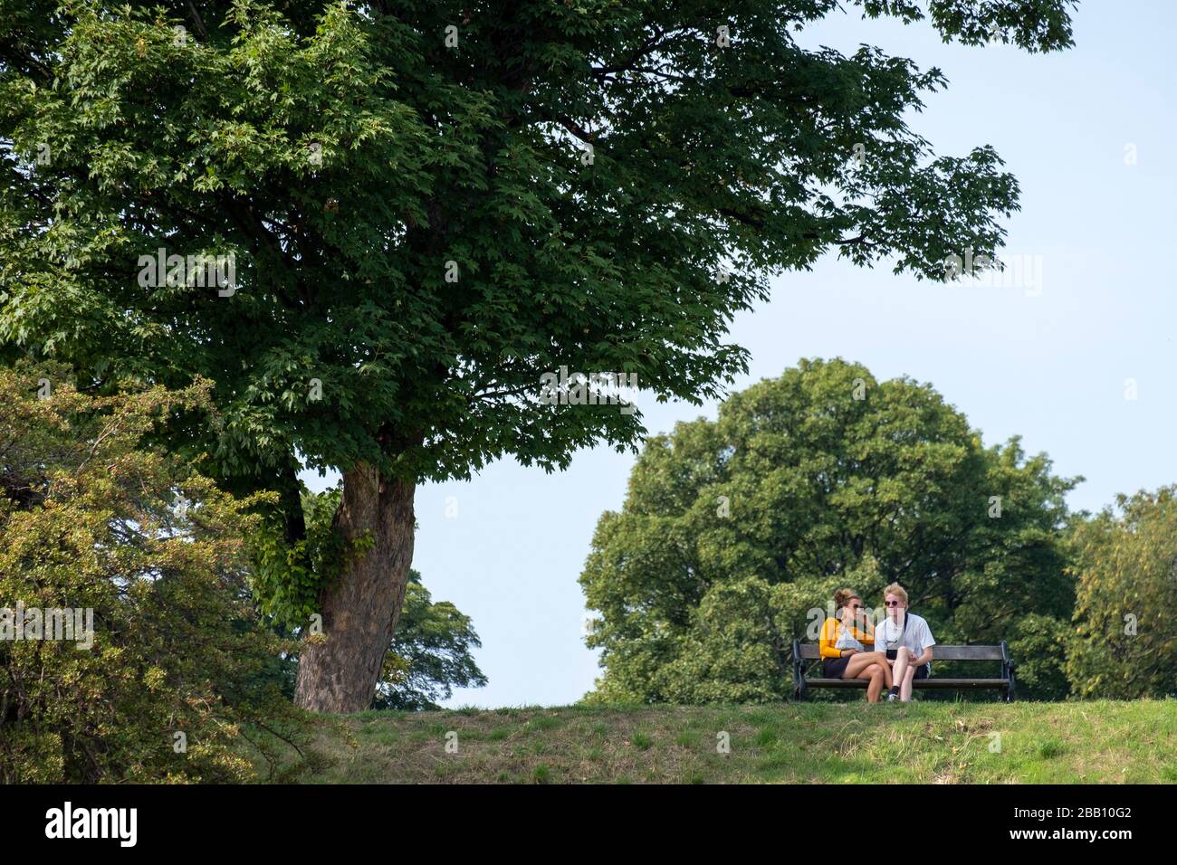 Man and woman sitting on a park bench Stock Photo - Alamy