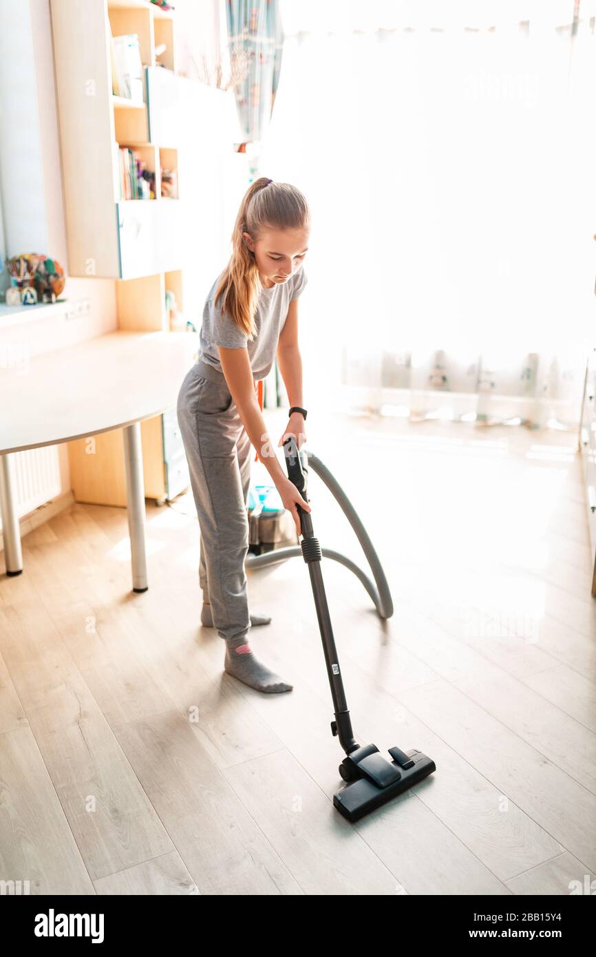 Teenage girl cleaning her room with vacuum cleaner. Children's tidiness and housekeeping help concept Stock Photo