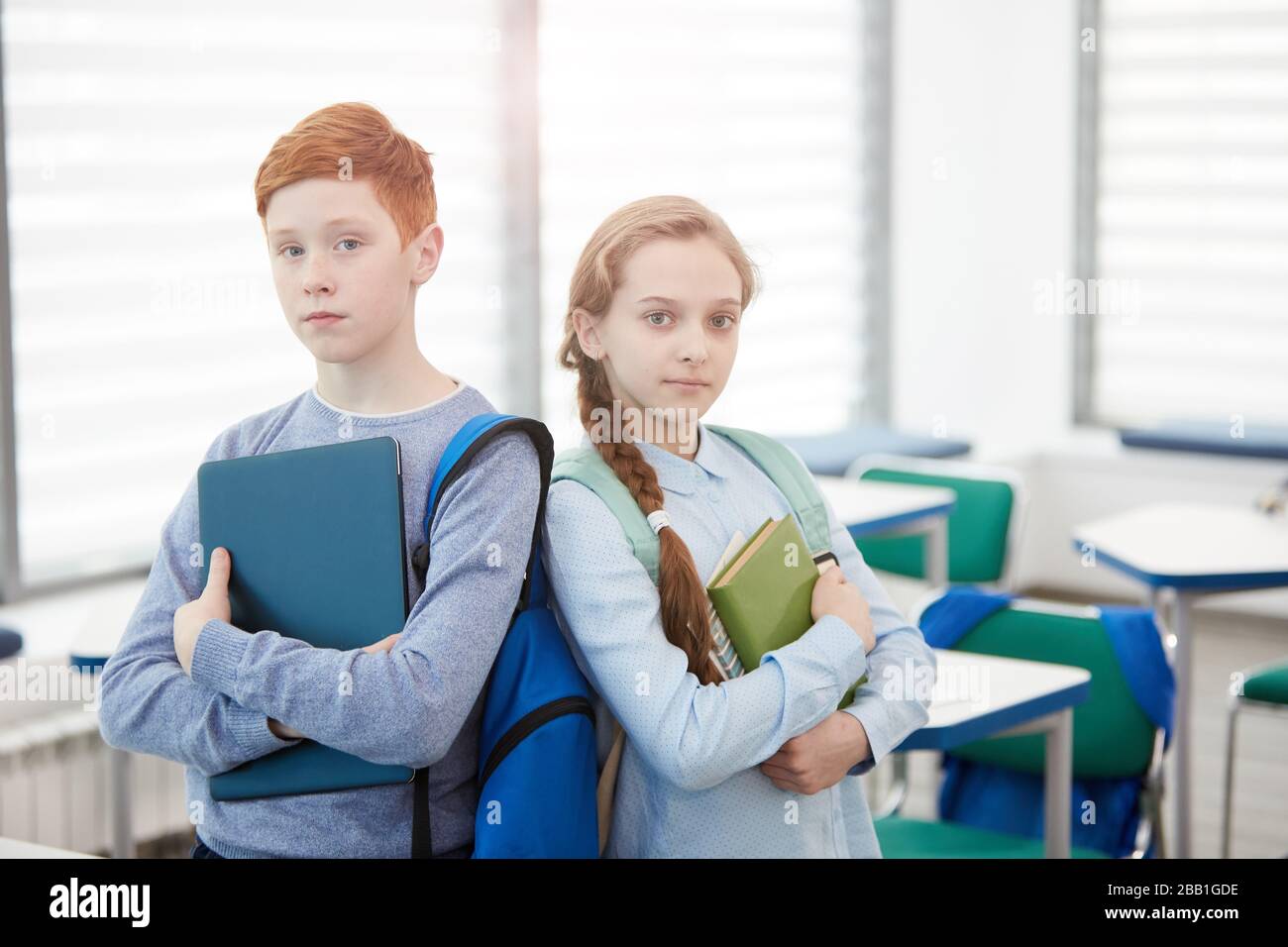 Waist up portrait of red haired teenage boy and girl standing back to ...