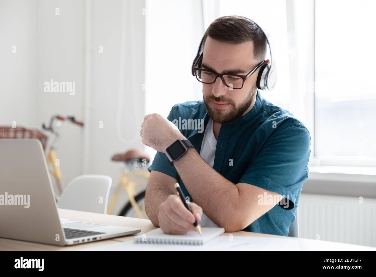 Focused man in headphones make notes working on laptop Stock Photo