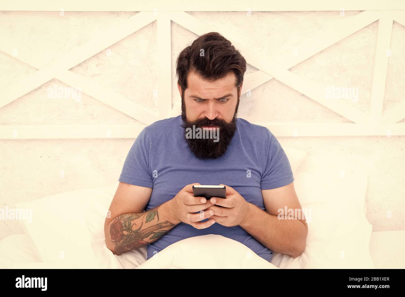 SMS communication. Bearded man use mobile phone in bed. Mobile communication. Cellular communication. Communication technology. Modern life. Stock Photo