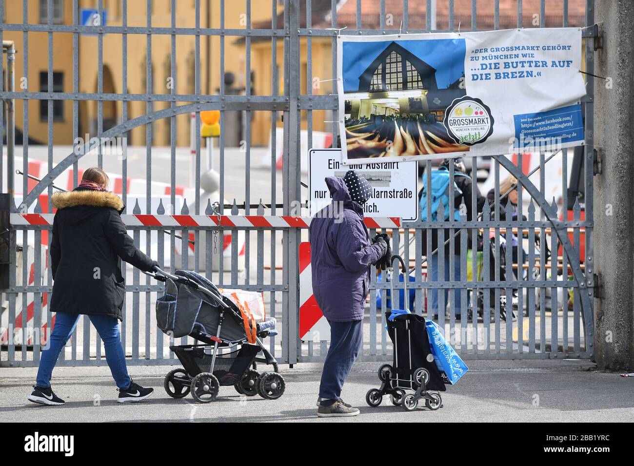 Needy people are waiting in front of the Muenchner Tafel in front of the  Muenchen wholesale market for food to be distributed. They wear protective  masks and pull their trolleys behind them. ?