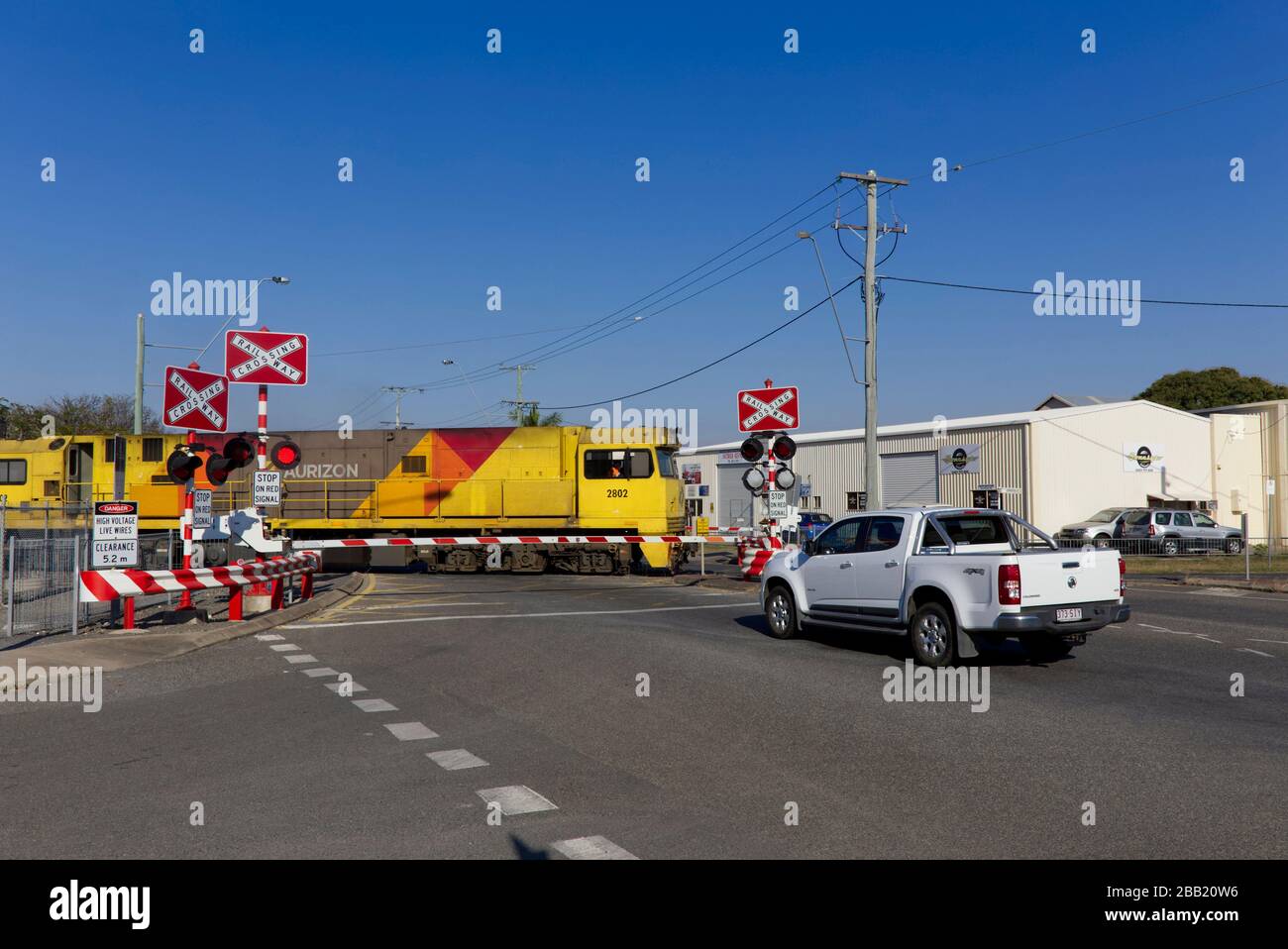 Traffic stopped at a level railway crossing in Rockhampton Queensland Australia for a north bound freight train. Stock Photo
