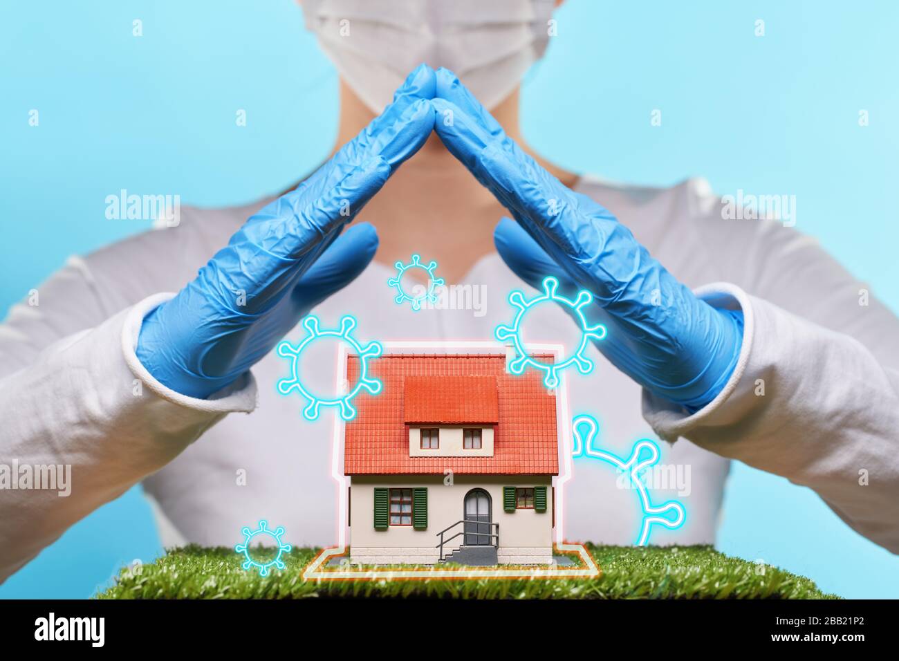 Woman in medical gloves and mask holds hands over a house. Concept of home stay, quarantine, security inside the house. Covid-19 Corona Prevention Mea Stock Photo