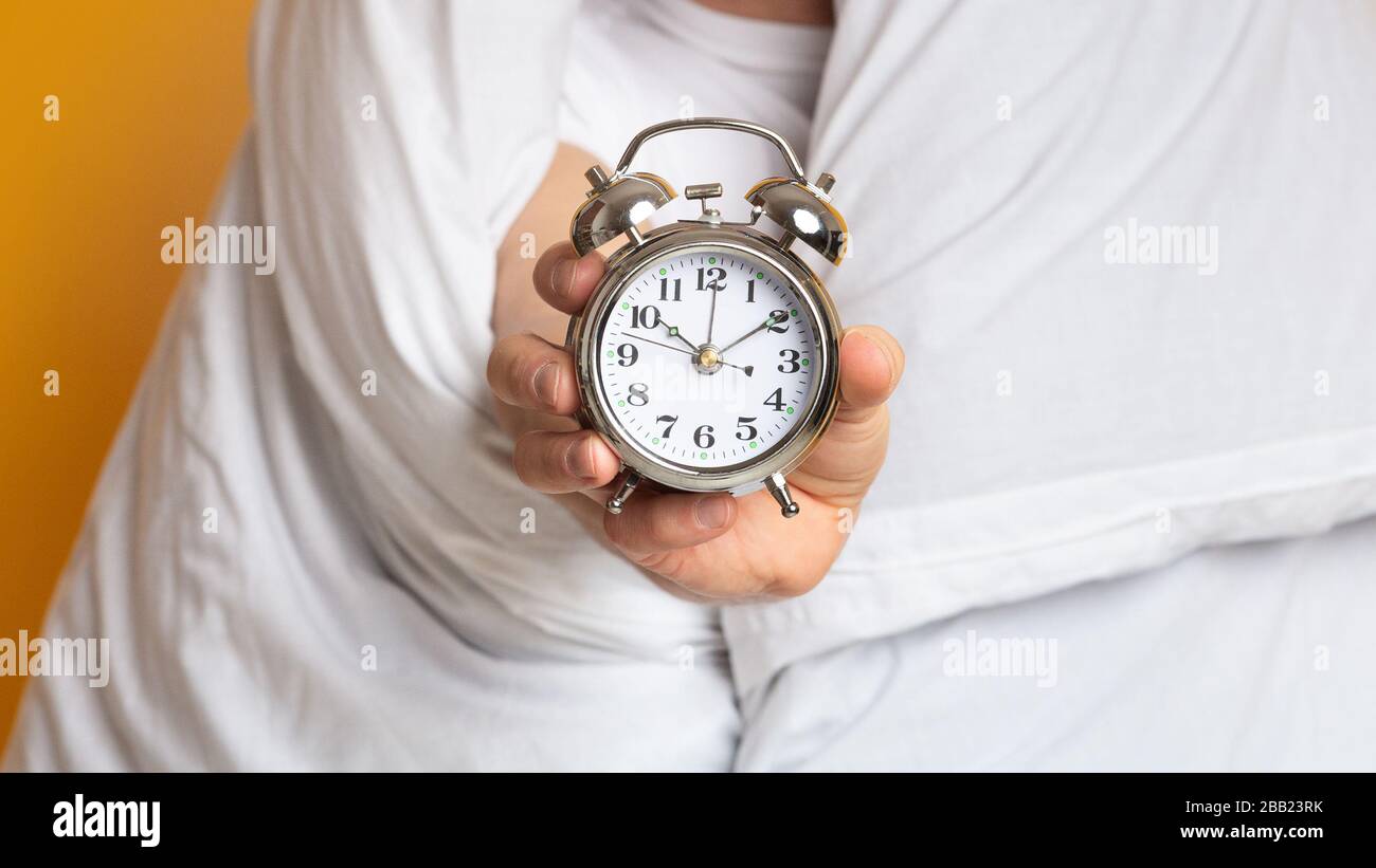 Man in blanket with an alarm clock Stock Photo
