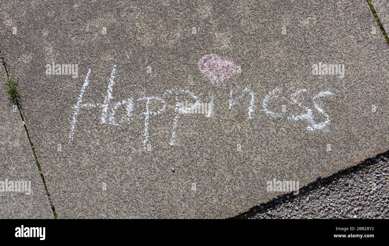 Word Happiness written on pavement with white chalk. With pink heart as dot for the i. Concept for postitive thinking, feeling happy, good vibrations. Stock Photo