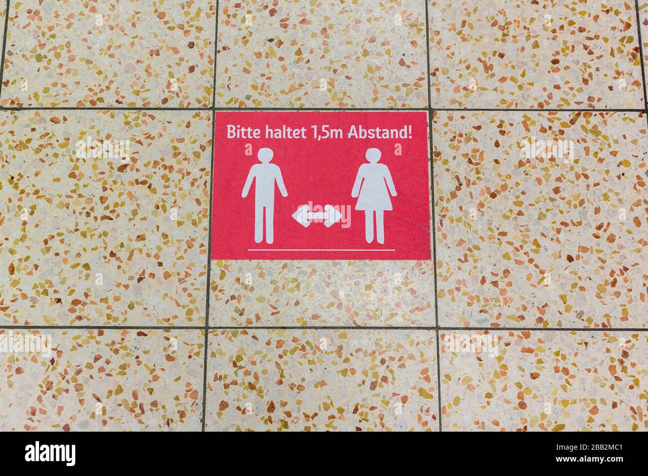 Sign on the floor of a Rewe supermarket. It reads 'Bitte haltet 1,5m Abstand!' (Please keep 1.5 meters distance). Due to Coronavirus. Stock Photo