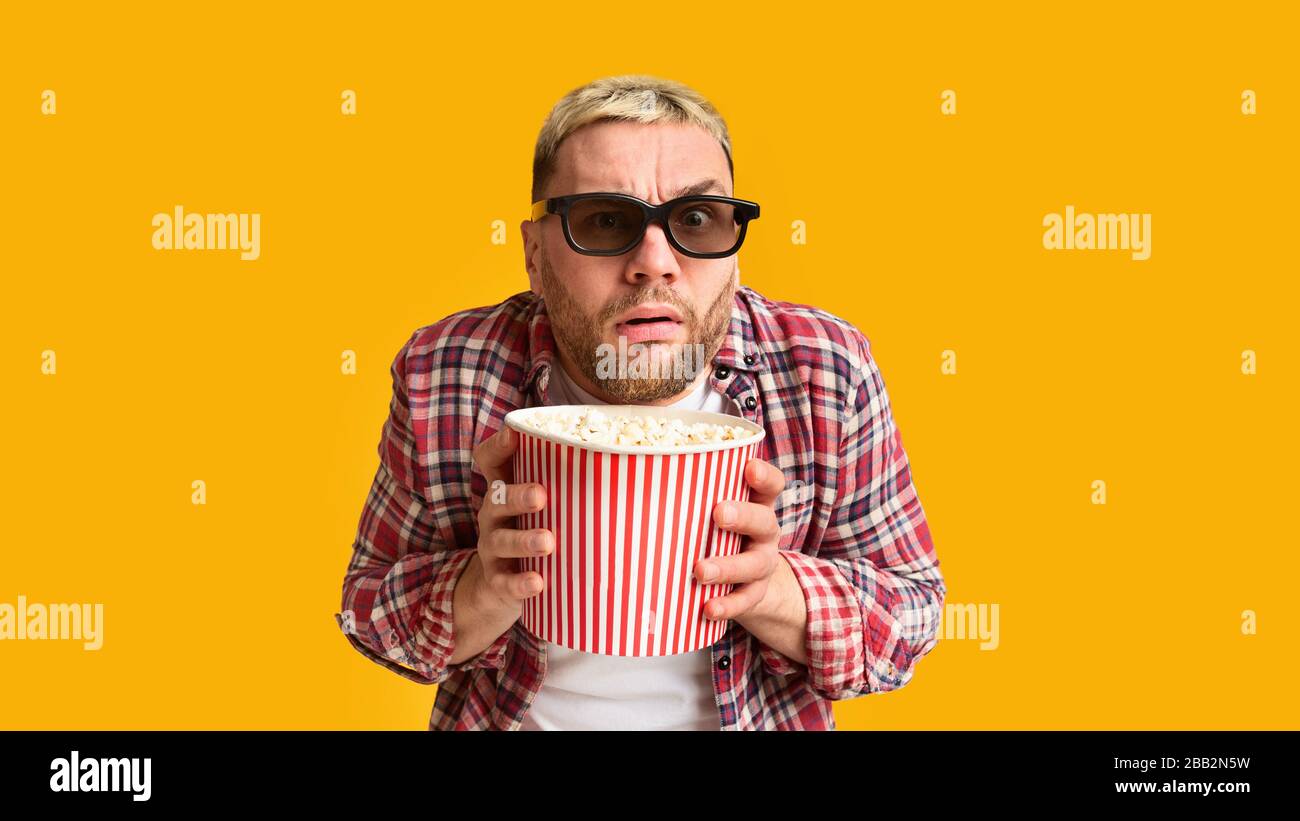 Emotional excitement from film. Funny guy hiding behind popcorn Stock Photo