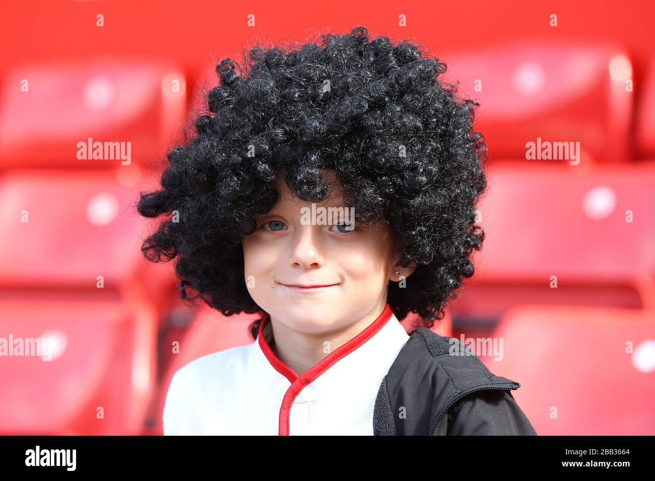 A young Manchester United fan wears a Marouane Fellaini wig in the stands at Old Trafford Stock Photo