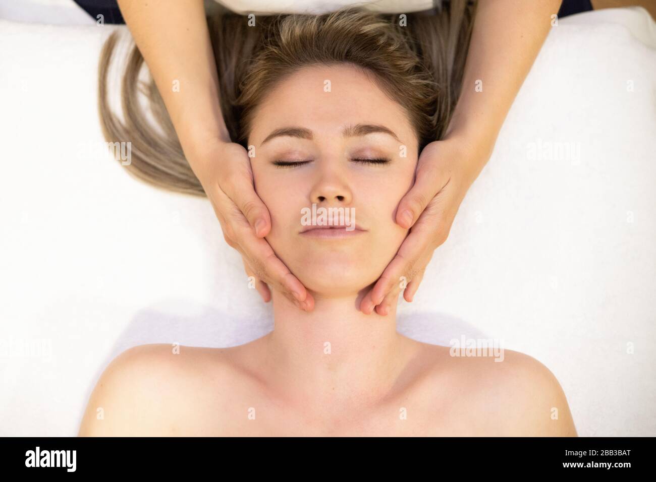 Young blond woman receiving a head massage in a spa center. Stock Photo