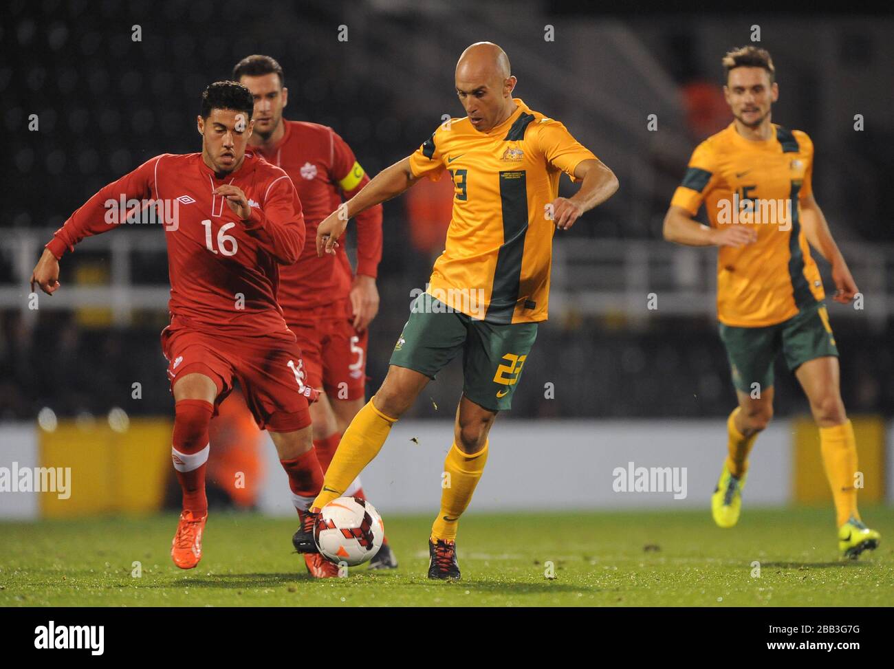 Australia's Mark Bresciano (centre) and Canada's Jonathan Osorio (left) battle for the ball. Stock Photo
