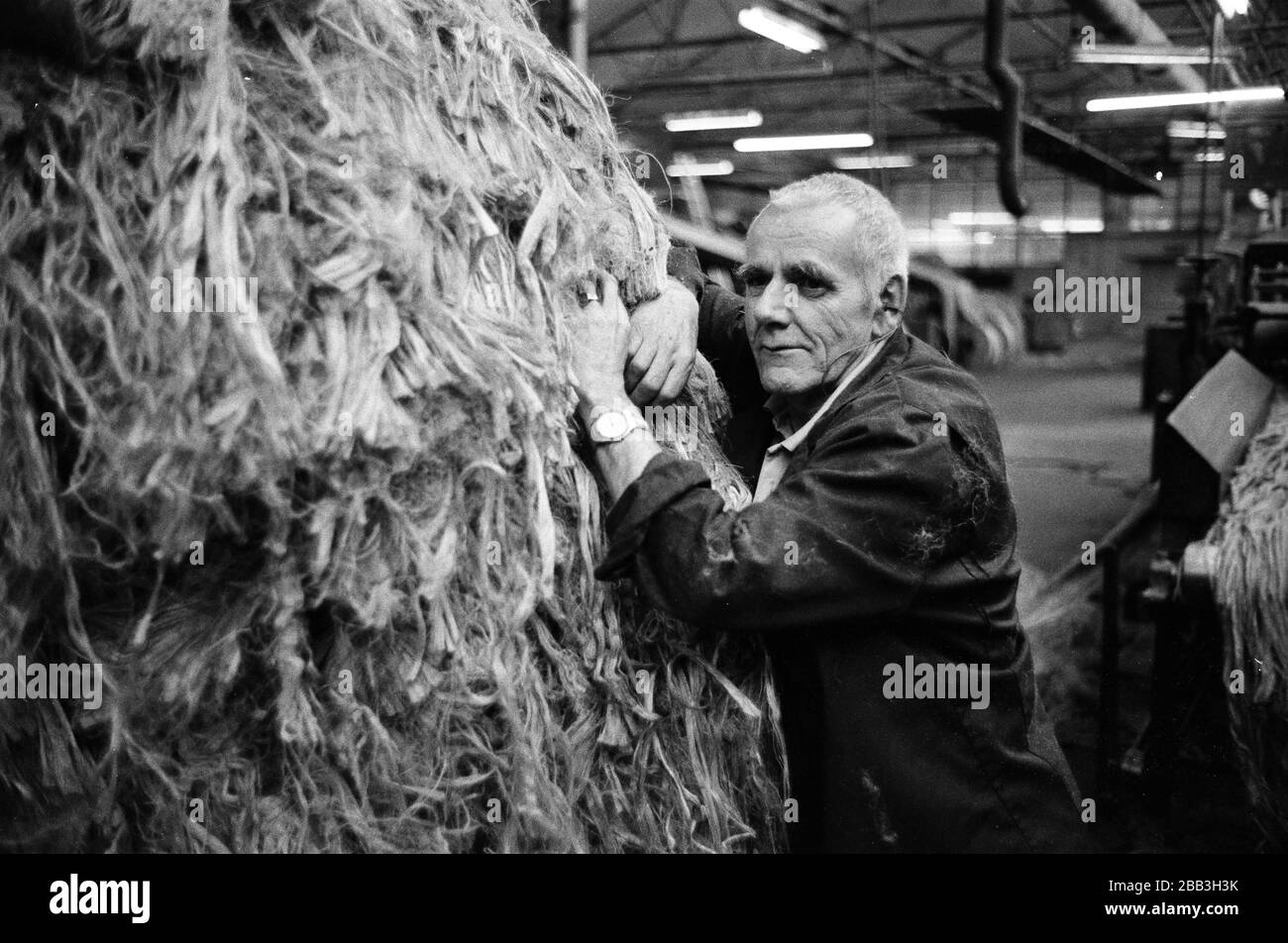 A worker leaning against bales of jute at Tay Spinners mill in Dundee, Scotland. This factory was the last jute spinning mill in Europe when it closed for the final time in 1998. The city of Dundee had been famous throughout history for the three 'Js' - jute, jam and journalism. Stock Photo
