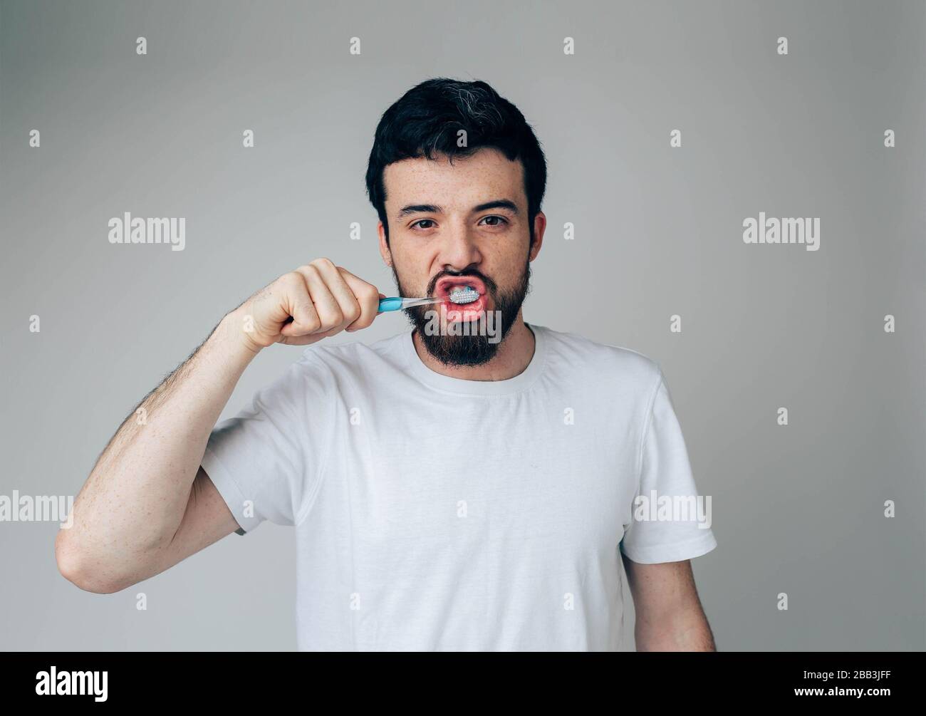 Young man isolated over background. Health and beauty concept - guy with toothbrush healthcare and sile treatment. Cleaning mouth Stock Photo