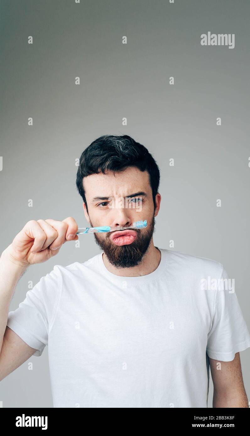 Toothbrush Playing Young man isolated over background. Vertical picture of serious funny ...