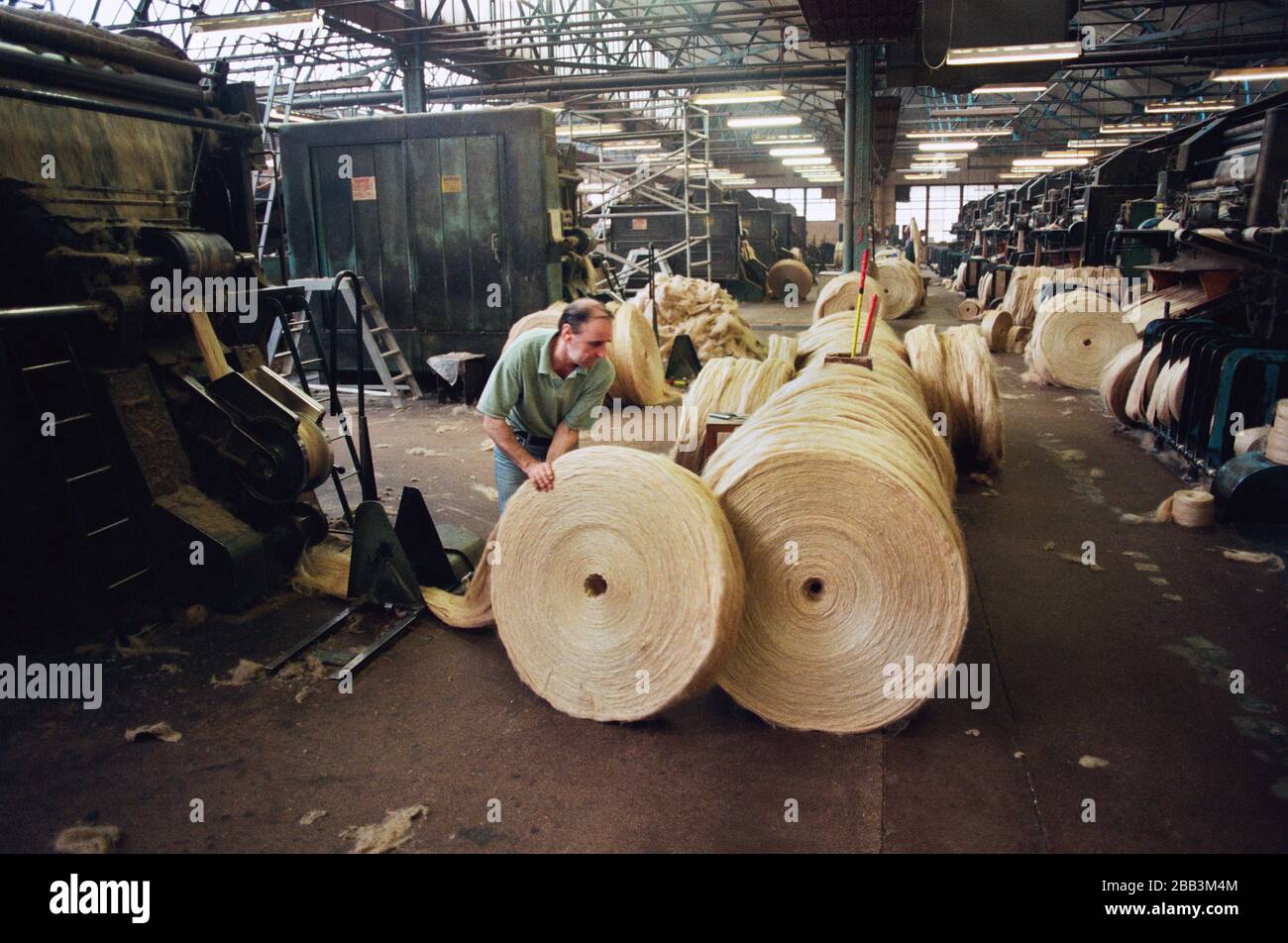 A worker rolling a circular bale of jute at Tay Spinners mill in Dundee, Scotland. This factory was the last jute spinning mill in Europe when it closed for the final time in 1998. The city of Dundee had been famous throughout history for the three 'Js' - jute, jam and journalism. Stock Photo