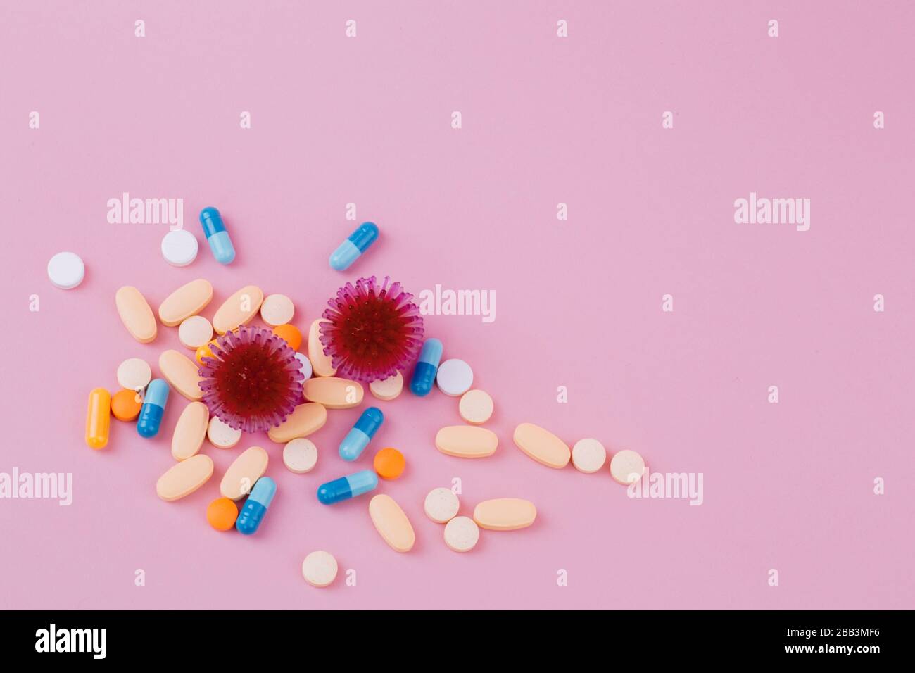 Abstract model of coronavirus infection of the strain Coronavirus.Red virus and a diverse pill on a pink background, the risk of a pandemic. Copy space. Stock Photo