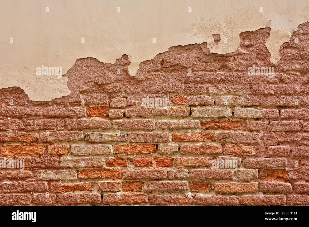 Old brick wall with peeling plaster, old background. Stock Photo