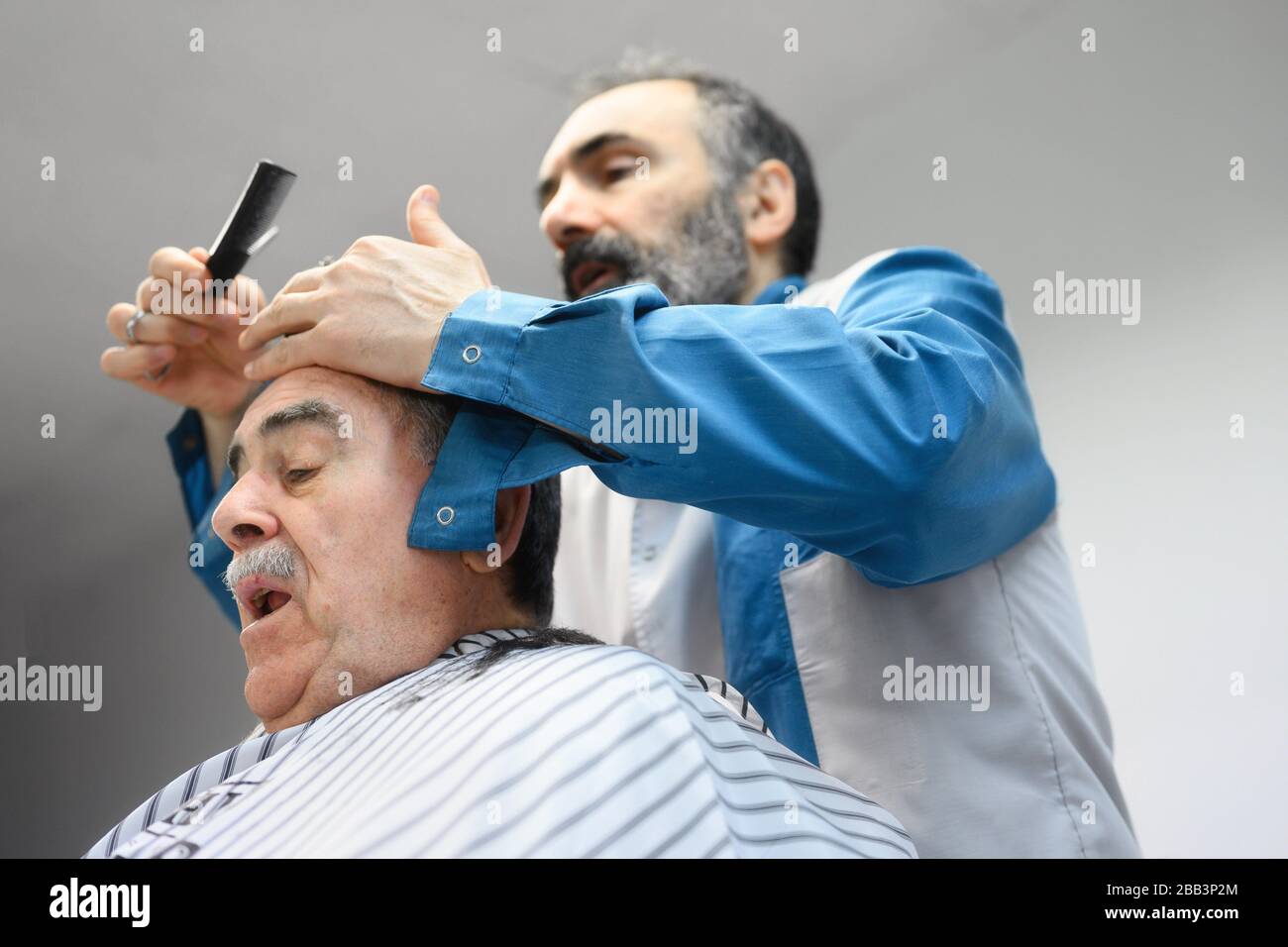 Barber trimming hair of old man at barber shop Stock Photo Alamy