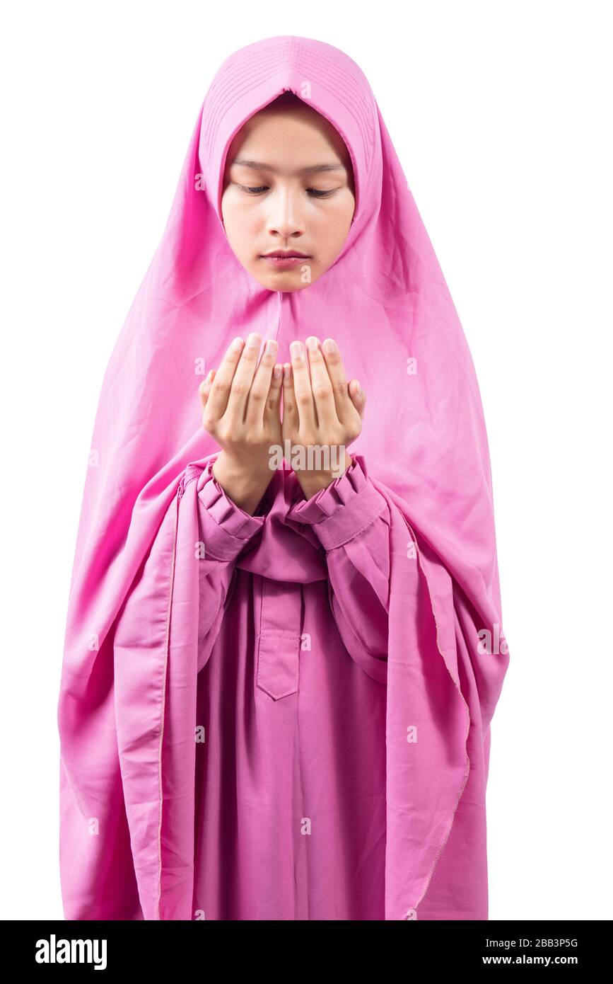Asian Muslim woman in a veil standing while raised hands and praying ...