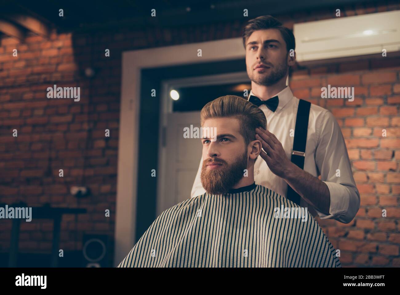 Attractive classy dressed barber shop hairdresser is turning client`s ...