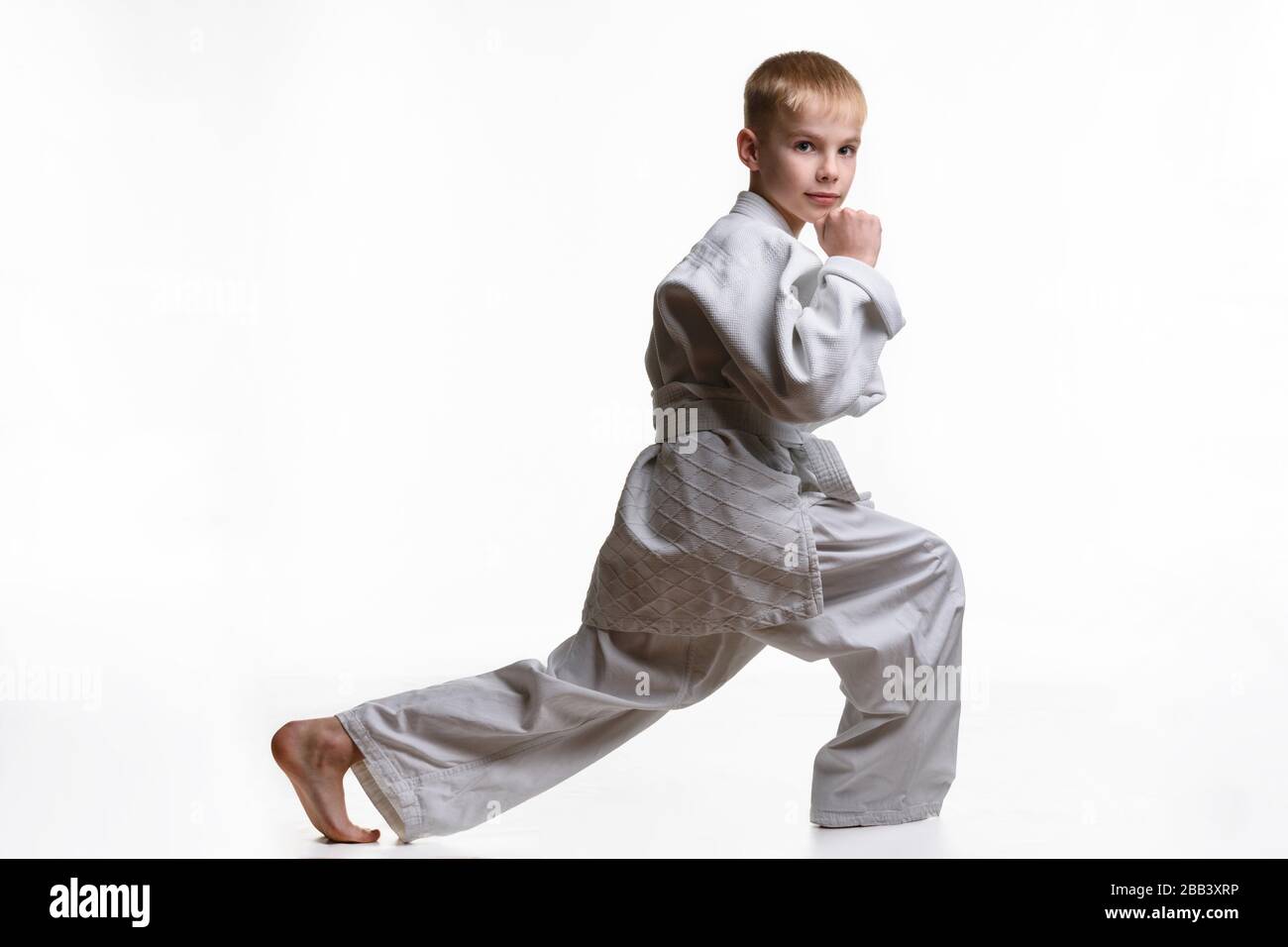 Martial arts student crouches, stretches his legs and looked into the