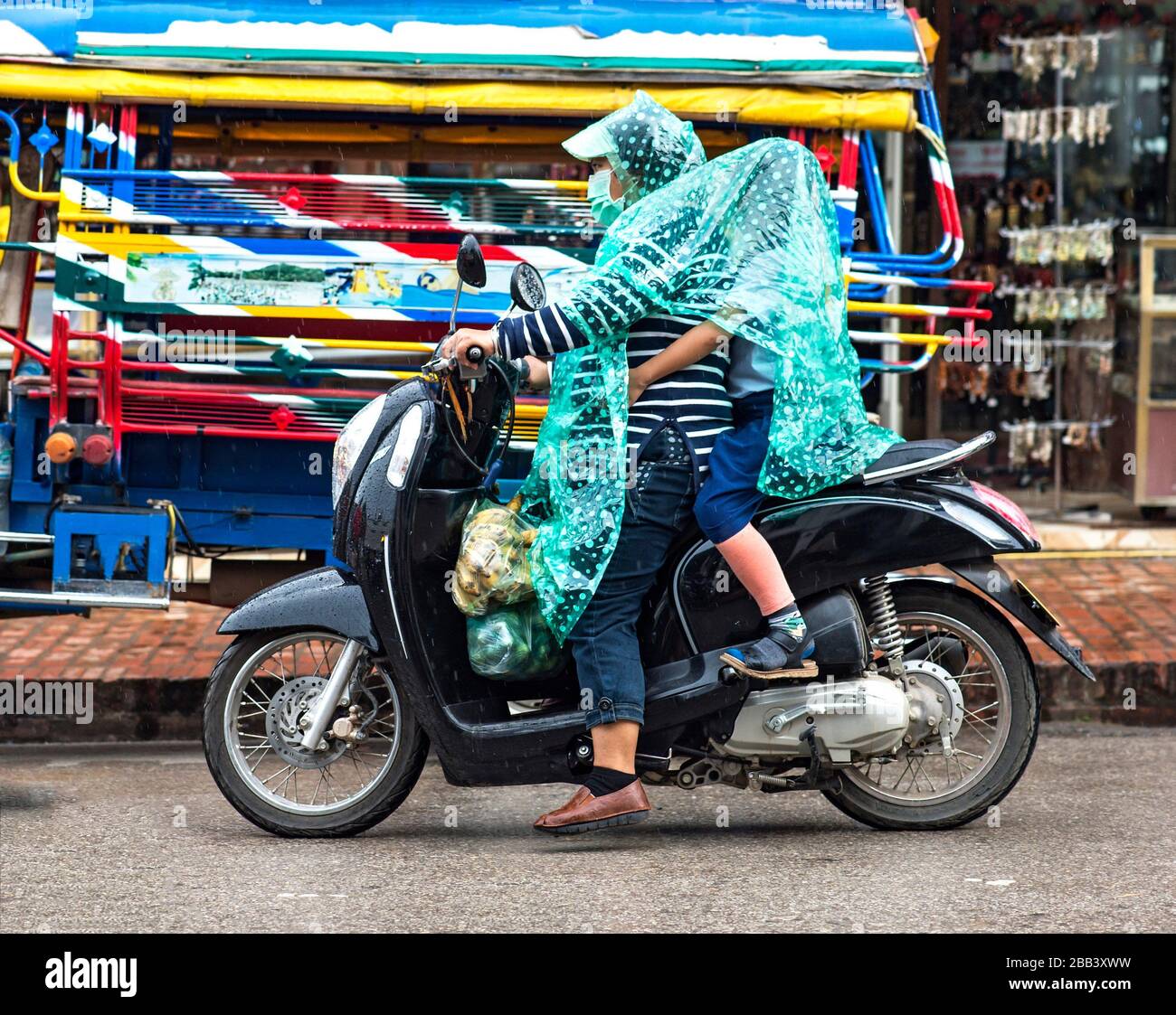 Riding in the rain, Luang Prabang, Laos. Stock Photo