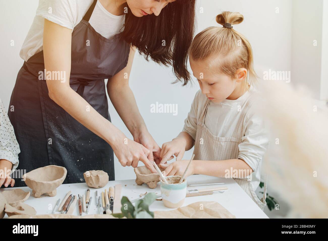 Close-up picture, master potter in an apron and a blond boy with long hair 7 years old, for a ceramics class Stock Photo