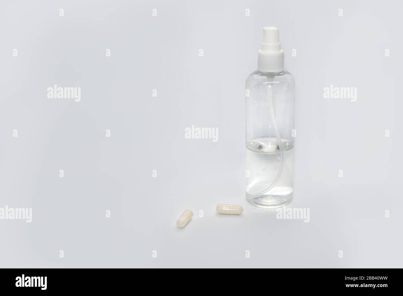 Spray trigger, white plastic pulverizer on white background with capsules pills. Sanitize spray cosmetics trigger. Aerosol transparent bottle close up Stock Photo