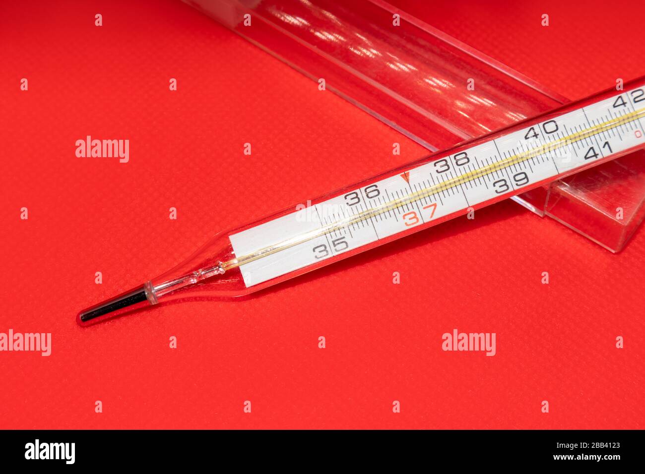 Thermometer macro, mercury instrument, measuring, indicating temperature medical equipment tool on vibrant red background Stock Photo