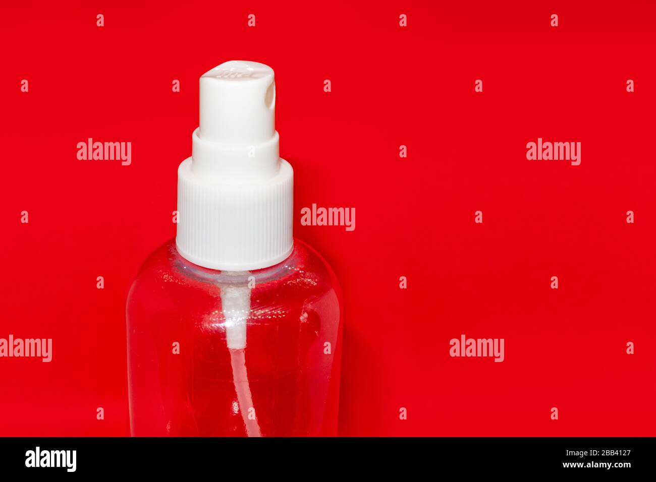 Spray trigger, white plastic pulverizer on red background. Sanitize spray cosmetics trigger. Aerosol transparent bottle close up. Clean care dispenser Stock Photo