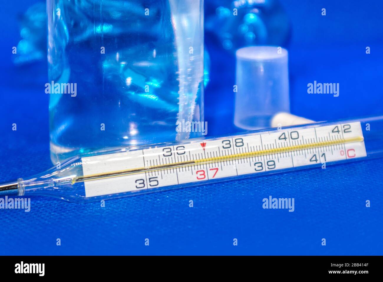 Thermometer macro, mercury instrument, measuring, indicating temperature medical equipment tool on vibrant blue background Stock Photo