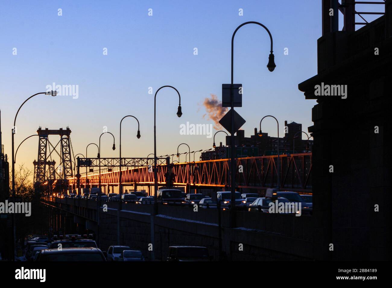 Cars on Lower East Side end of Williamsburg Bridge in the early morning rising sun in New York City, United States of America Stock Photo