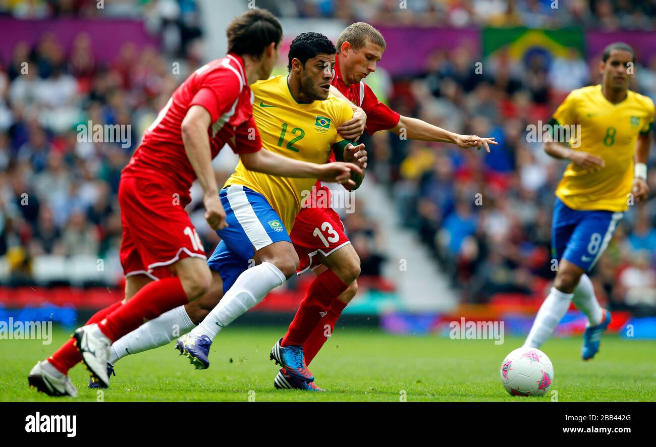 Brazil's Hulk battles for possesion with Belarus Mikhail Gordeichuk and Llya Aleksievich during the Brazil v Belarus Group C match at Old Trafford, Manchester. Stock Photo