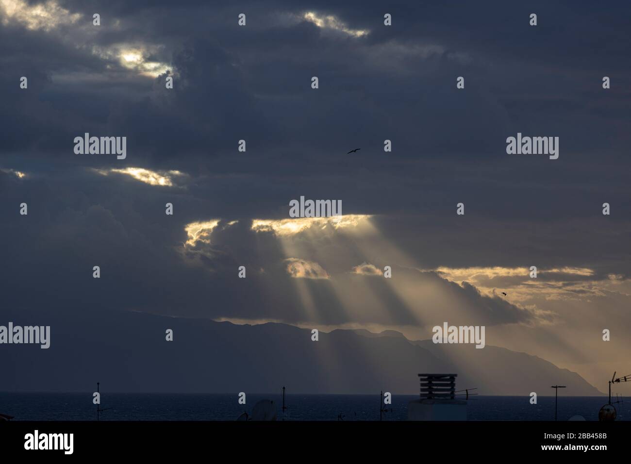 Suns rays shine through the clouds on to the sea,Playa San Juan, Tenerife, Canary Islands, Spain. Stock Photo